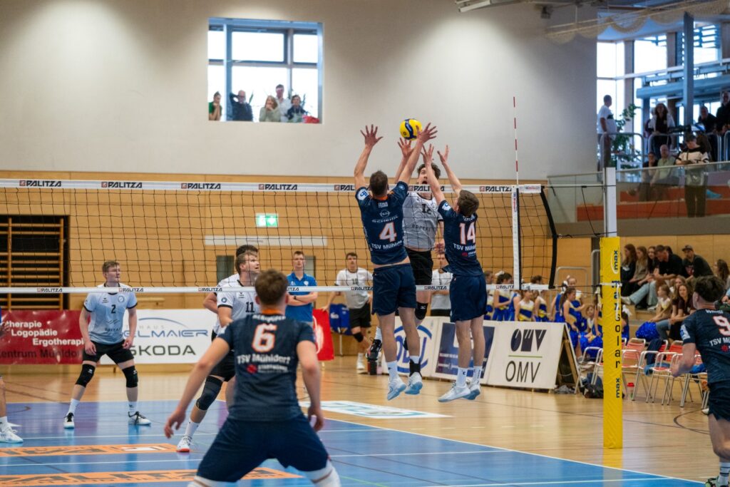Am Samstagabend verabschiedete sich der TSV Mühldorf mit einer Heimniederlage gegen den frischgekrönten Meister der 2. Volleyball-Bundesliga Süd, die Blue Volleys Gotha, aus der heimischen NUTZ-Arena. In drei Sätzen (19:25, 18:25, 14:25) setzte sich das überragende Team aus Thüringen souverän durch und untermauerte einmal mehr seine Ausnahmestellung in der Liga. Mühldorf, das aktuell auf einem respektablen sechsten Tabellenplatz steht, blieb trotz kämpferischer Leistung chancenlos – hat aber mit dem letzten Saisonspiel am 26. April in Mimmenhausen noch einen wichtigen Auftritt vor sich. Im ersten Satz zeigten die Gäste sofort, warum sie an der Tabellenspitze stehen. Druckvolle Aufschläge, präzise Zuspiele und ein stabiler Block setzten Mühldorf früh unter Zugzwang. Die Hausherren hielten zunächst wacker mit und konnten den Rückstand zwischenzeitlich verkürzen, doch Gotha blieb cool und zog das Tempo gegen Satzende erneut an. Mit 25:19 ging der erste Satz verdient an die Gäste. Der zweite Satz verlief aus Mühldorfer Sicht ähnlich: engagierter Beginn, lautstarke Unterstützung von den Rängen, doch Gotha blieb in jeder Phase abgeklärt. Besonders im Angriff überzeugten die Thüringer mit hoher Durchschlagskraft und Spielwitz. Mühldorf konnte in der Annahme und im Spielaufbau nicht immer stabil bleiben, wodurch sich die Gäste mit zunehmender Dauer deutlich absetzen konnten. Der Satz endete mit 25:18 für Gotha. Der dritte Satz war dann die deutlichste Angelegenheit des Abends. Mühldorf fand kaum noch Zugriff aufs Spiel. Die Fehlerquote stieg, während Gotha nahezu fehlerfrei aufspielte. Mit einem 25:14 setzten die Blue Volleys schließlich den Schlusspunkt unter einen insgesamt einseitigen Abend. Trotz der klaren Niederlage gab es auf Mühldorfer Seite auch Lichtblicke: Mittelblocker David Fecko zeigte eine starke Leistung und wurde verdient zum MVP seiner Mannschaft gewählt. Mit wuchtigen Angriffen und cleveren Blocks sorgte er für die auffälligsten Akzente im Spiel der Gastgeber. Bei den Gästen wurde Erik Niederlücke ausgezeichnet wegen seiner Konstanz im kompletten Spiel. Kapitän Fabian Bartsch, der sein Team über die gesamte Saison hinweg mit viel Engagement und Einsatz geführt hat, betonte nach dem Spiel die Bedeutung des bevorstehenden Auswärtsspiels in Mimmenhausen am 26. April. "Wir wollen die Saison mit einem positiven Gefühl abschließen und nochmal alles raushauen", so Bartsch. Der TSV Mühldorf kann trotz der Niederlage mit dem bisherigen Saisonverlauf zufrieden sein. Platz sechs in einer starken Liga ist ein klares Zeichen für den positiven Weg, den das Team eingeschlagen hat. Die Mischung aus jungen Talenten und erfahrenen Spielern lässt für die kommende Saison hoffen – und vielleicht ist man dann in solchen Spielen näher dran am Favoriten. Gotha hingegen verabschiedete sich mit einem Ausrufezeichen von der Zweitligabühne. Der Meistertitel ist mehr als verdient – und der Auftritt in Mühldorf war ein letzter, eindrucksvoller Beweis dafür. ged/David Geisberger